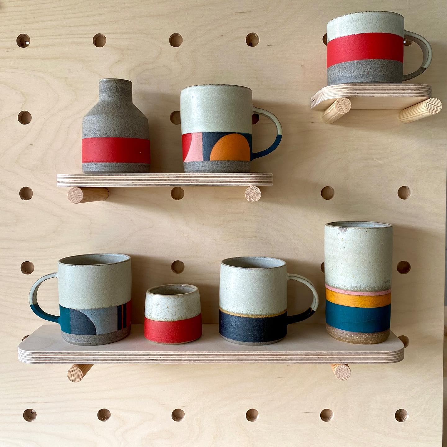 Mugs on a wooden shelf with pegs, offering clever storage for a more efficient home.