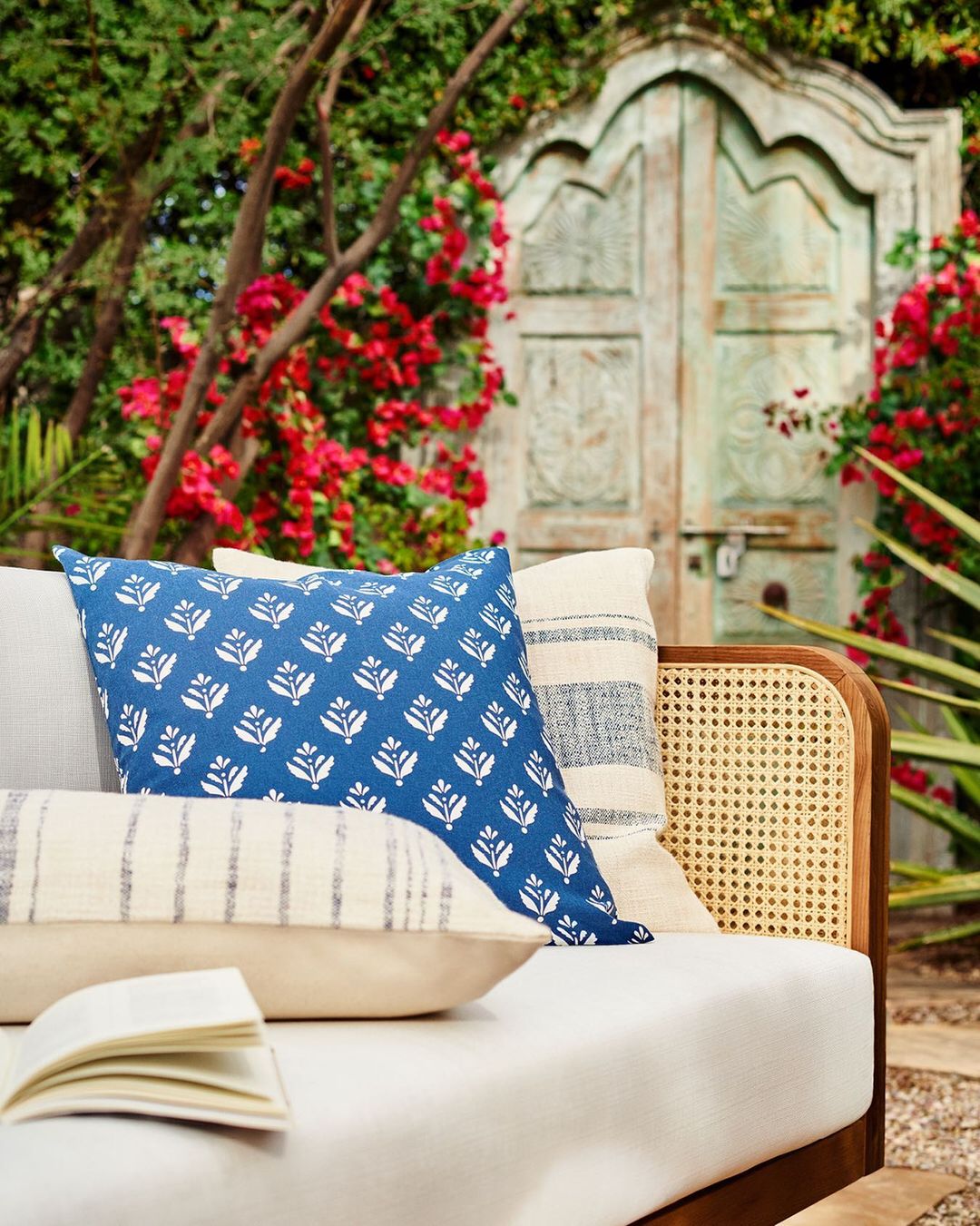A couch with a book on it and styled with patterned pillows, perfect for creating your own summer home decor paradise.