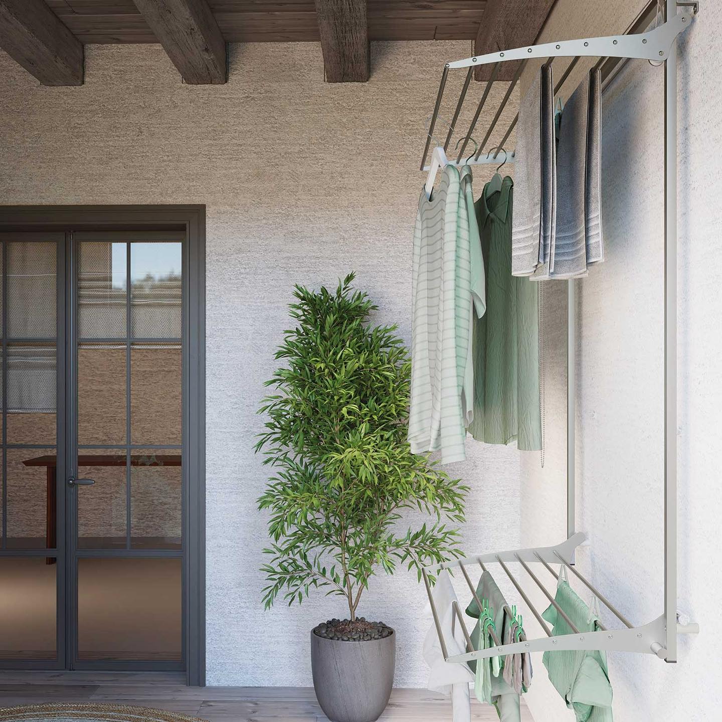 A clothes drying rack on a patio next to a potted plant offers an efficient and clever use of an otherwise under-utilized outdoor wall space.