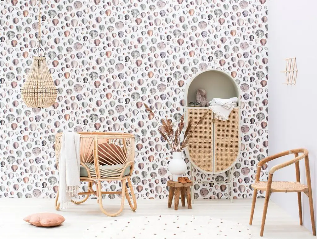 Interior decor featuring a rattan chair, a small stool, a decorative mirror, and a hanging light, set against a kid's bedroom-themed wallpaper.