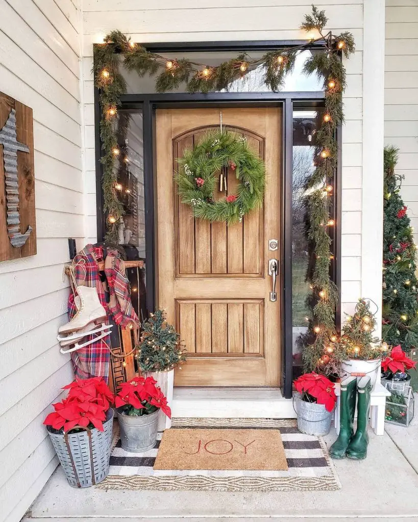 Christmas front porch decor with string lights around a wooden door with sidelights and floor vignettes using Christmas-inspired items