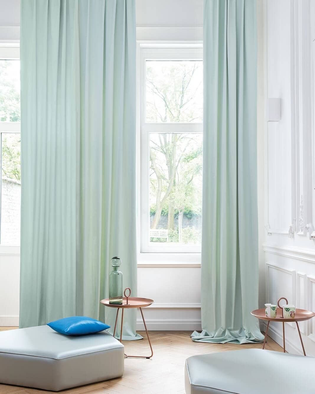 long pastel curtains over two long windows in a living space filled with natural light