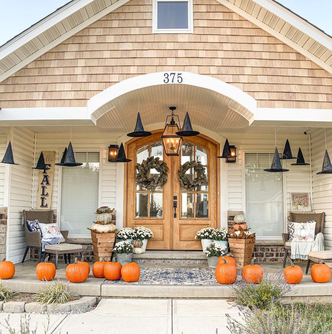 a double-door fall front porch decor with orange pumpkins on the floor in front of the porch