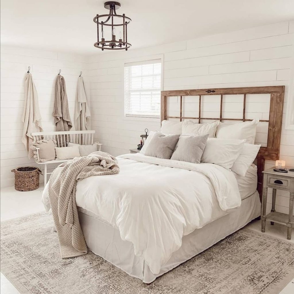 a farmhouse style bedroom with a natural wood headboard bed and area rug