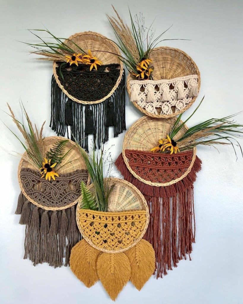 Six Bohemian wall hangings made of woven fibers with various patterns, adorned with fringes and botanical embellishments, displayed on a white wall.