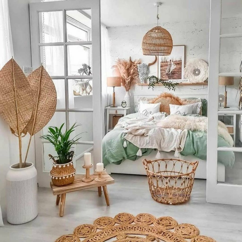 A serene bedroom featuring a colorful mint green and white color scheme with natural decor elements like wicker and dried leaves, and large windows allowing ample natural light.