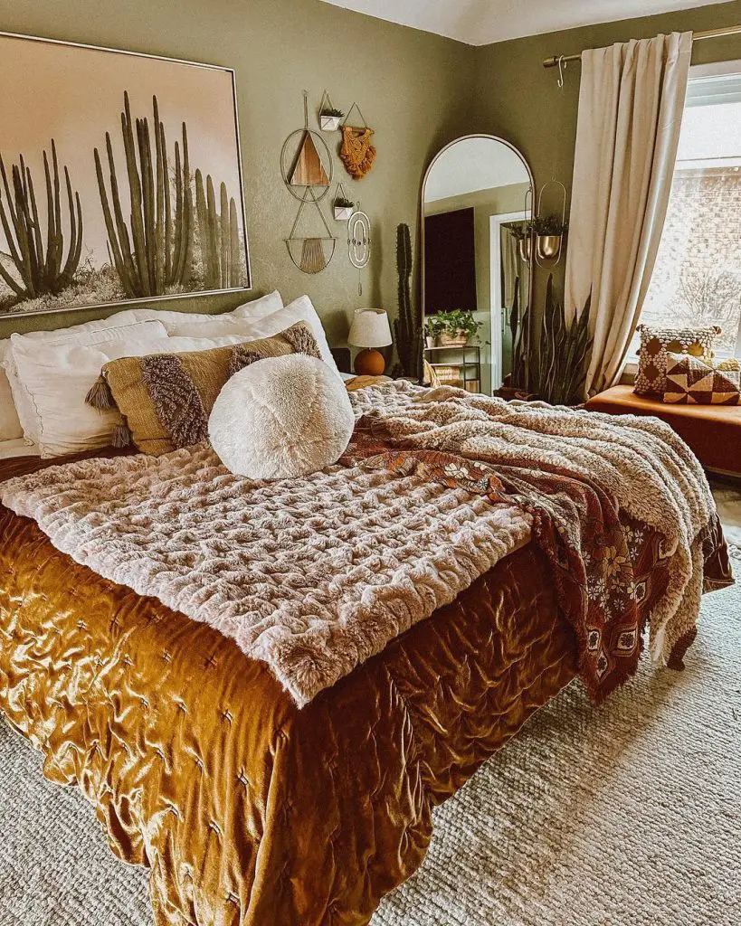 Cozy bedroom with a plush bed covered in decorative blankets, surrounded by textural eclecticism and large cactus artwork above the bed.