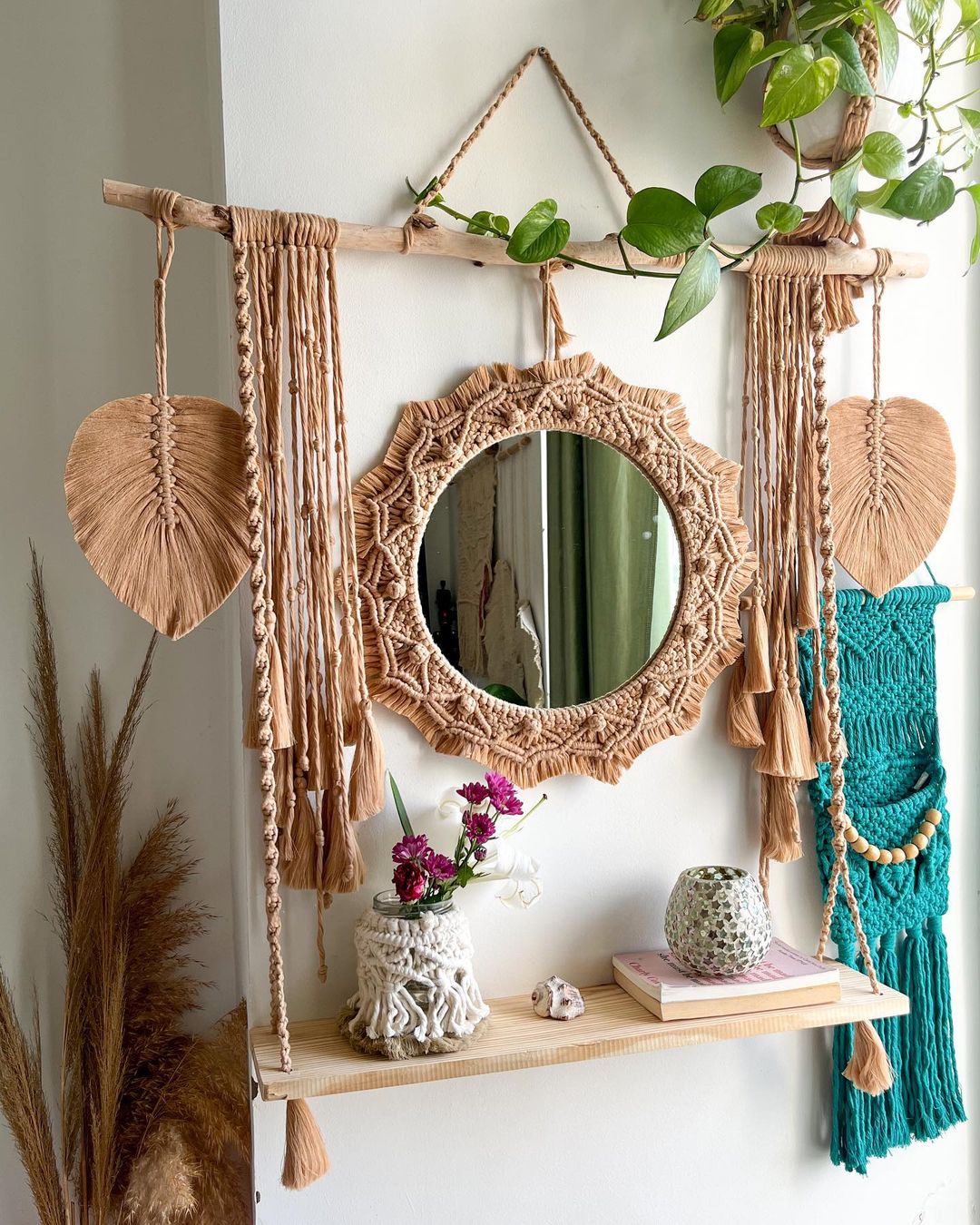 styling your macrame wall hanging does not have to be difficult, a mirror, shelf with personal items, and some green leaves can work wonders in achieving your favorite bohemian look