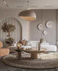 Modern living room with a white sofa, beige accents, round wooden coffee table, unique wall decorations, large hanging light fixture, and a textured rug. Embracing minimalist living inspired by Japandi decor, the space is enhanced with plants and dried flowers for a serene atmosphere.