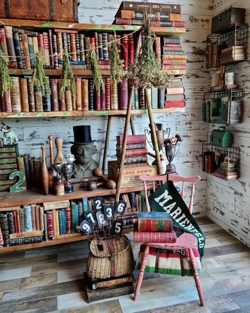A room with vintage decor including shelves of old books, dried herbs, trophies, and antique items, perfect for one of the 10 Inspiring Home Office Library Designs for Every Decor Style. A stack of books sits on a red chair, and various knickknacks are displayed on the shelves and floor.
