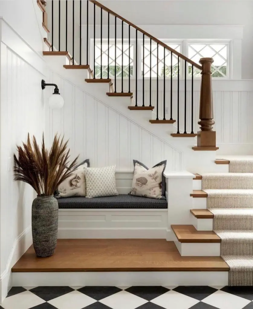 a cozy stair nook bench in front of an elegant stair with metal and wood balustrade