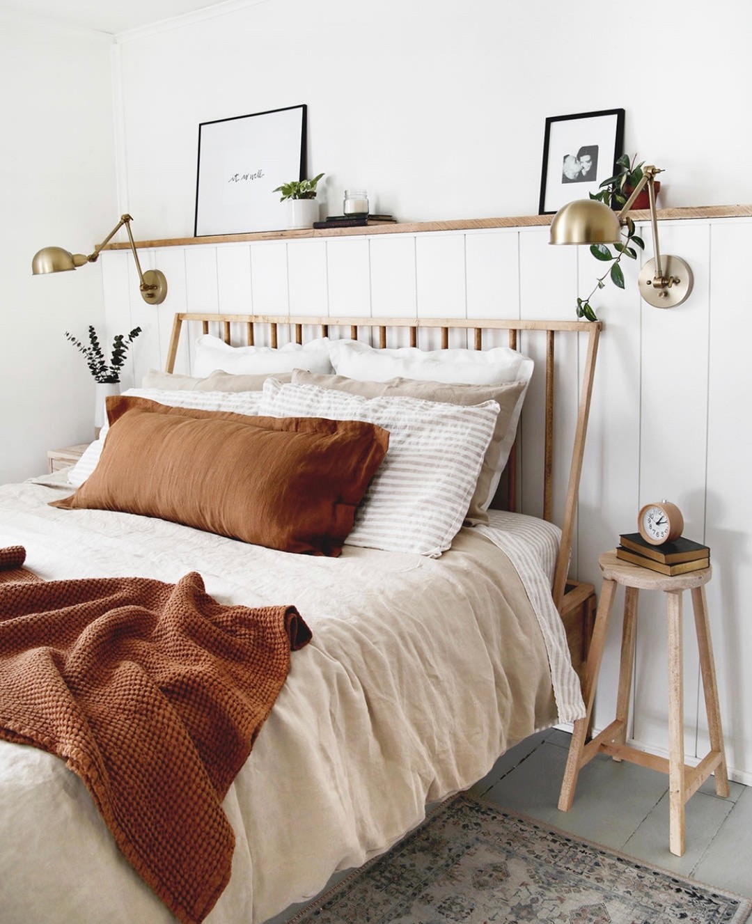 bedroom focusing on a simple yet elegant vertical strips wooden headboard, styled with wall lamps on each side of the bed and layered pillows and matching bedding