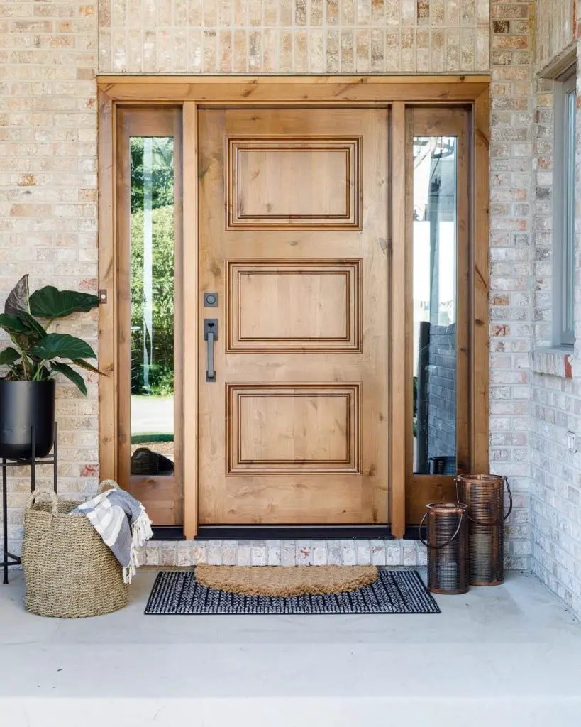 the outside of a front door with sidelights, layered doormat, a potted plant, a basket, and other decorative elements on the floor