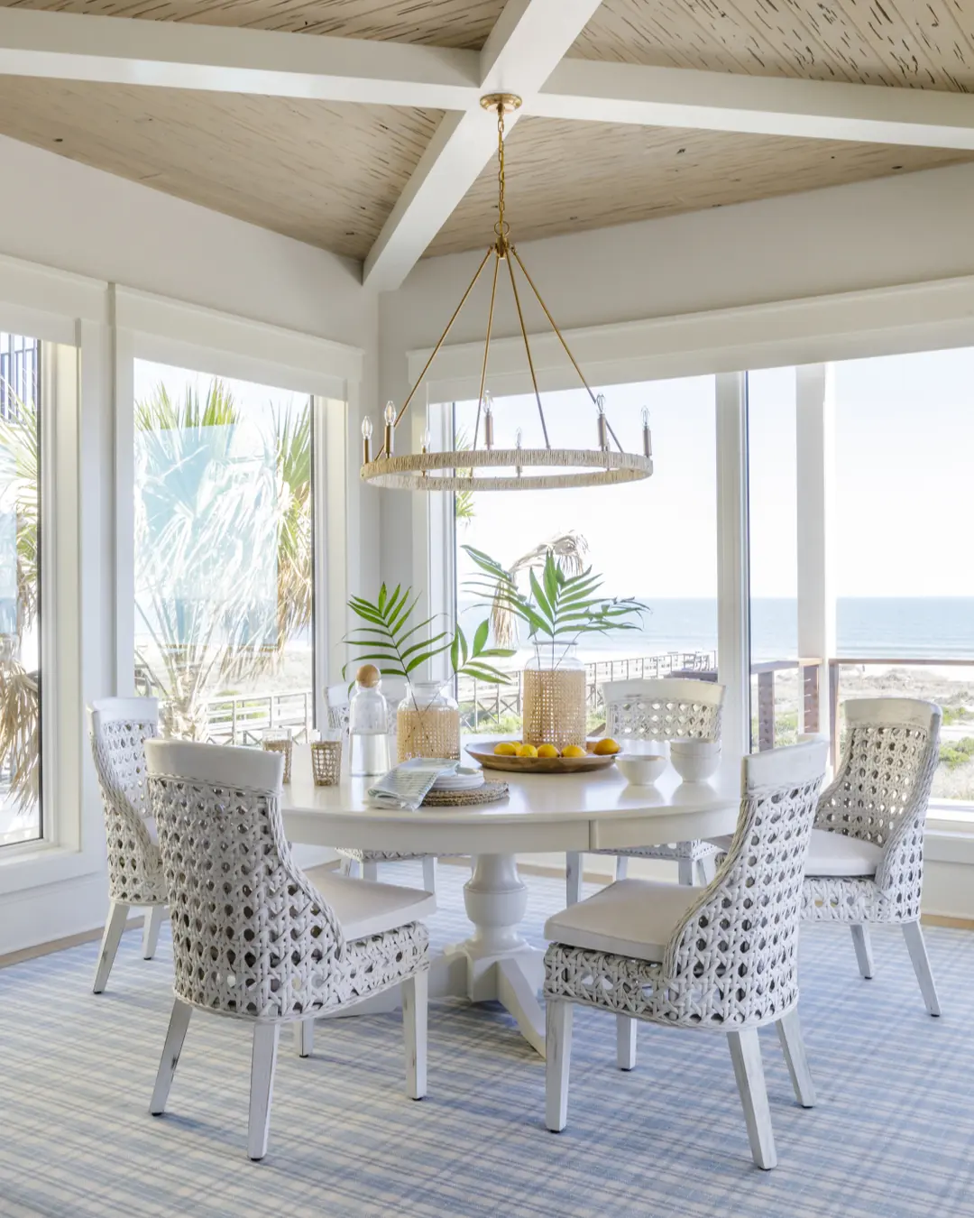 large glass windows and doors add an airy and bright feel to this coastal-inspired dining room interior. 