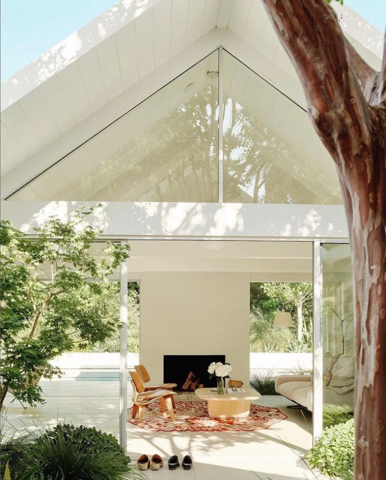 Eichler Homes front with large open glass doors opening into a living room all painted in white