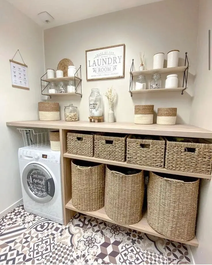A neatly organized laundry room with a washing machine, wicker baskets, jars, and shelving units holding various items showcases how creative storage hacks can transform your laundry area. A sign reading "Laundry Room" hangs on the wall. The floor features patterned tiles.