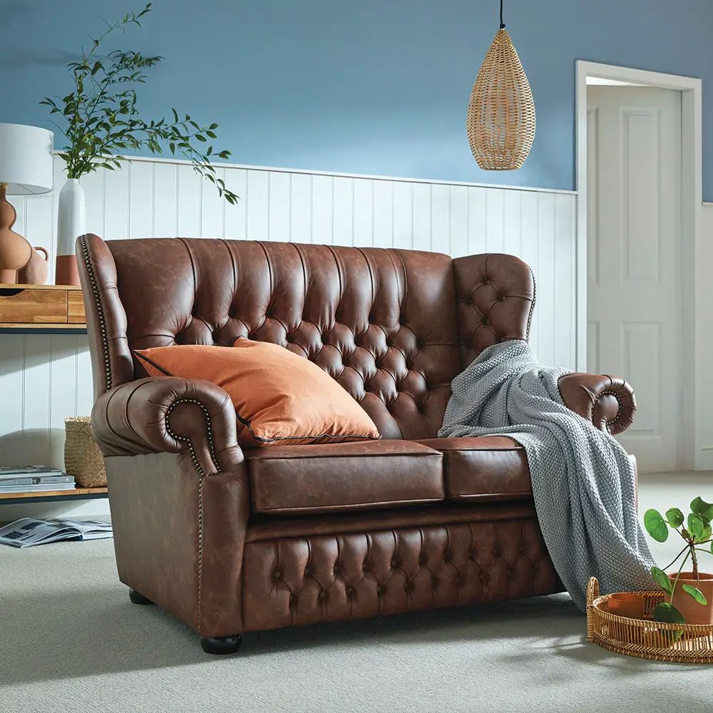 a Canterbury 2 seater with a fully buttoned back, styled with a throw blanket and pillow in a living space is an excellent example of a Furniture That Stand the Test of Time