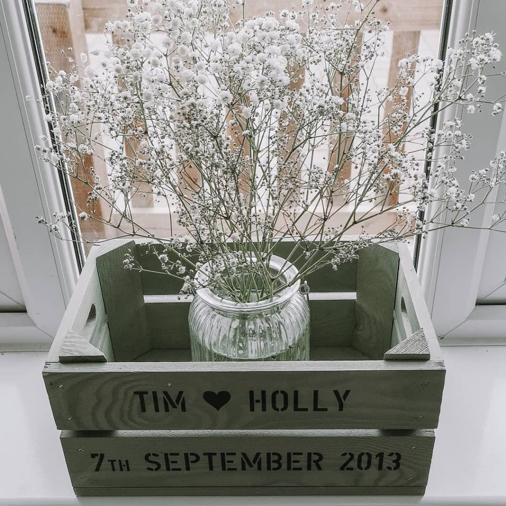 glass jar used as a flower vase in a sage colored wooden crate on a window sill