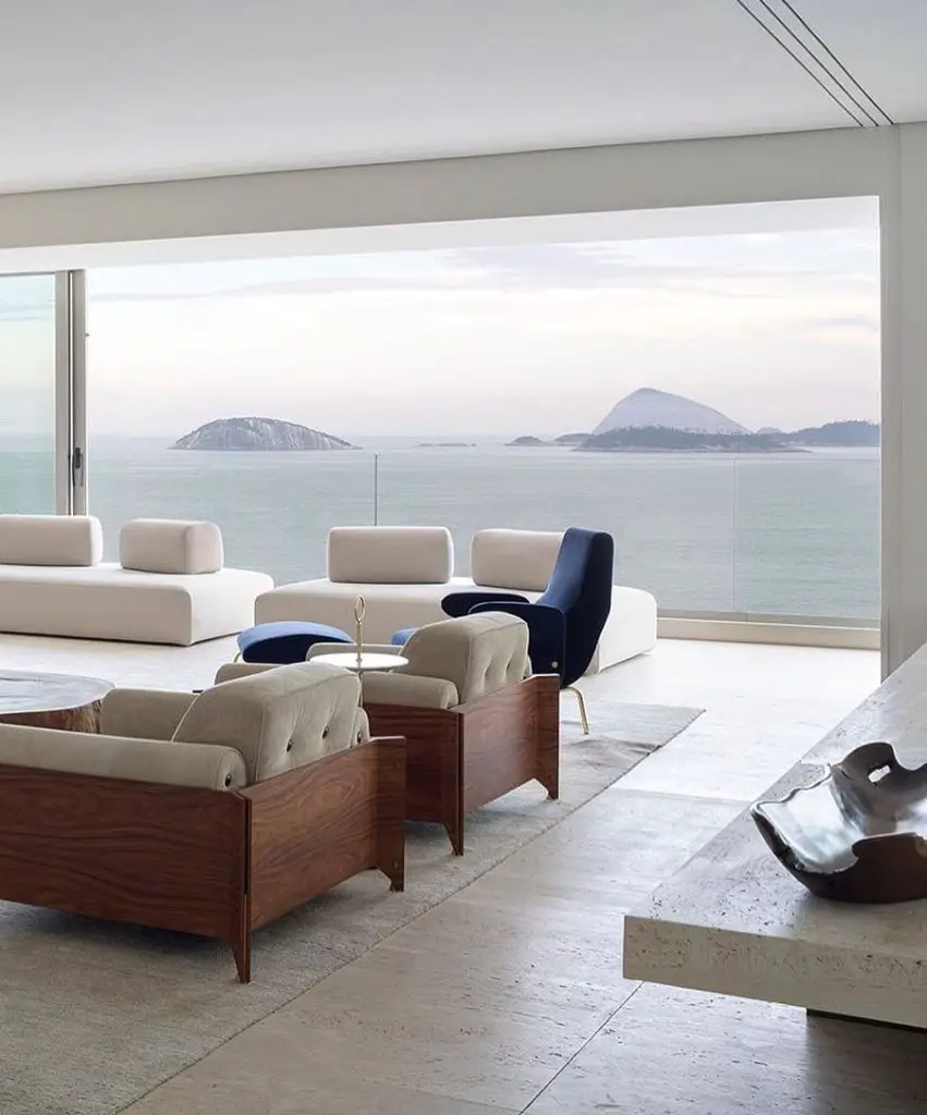 A modern living room with minimalist furniture, featuring large windows showcasing a scenic ocean view with islands on the horizon, elegantly illustrates Zen home decor: how to elevate the peaceful aura of your living space.