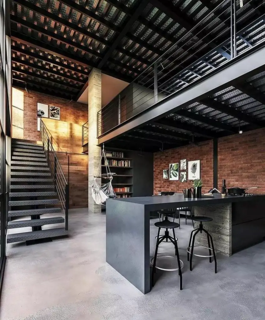 Industrial style loft space with double volume, a metal staircase, kitchen countertop, some stools, a metal mezzanine above the kitchen, and a metal ceiling above