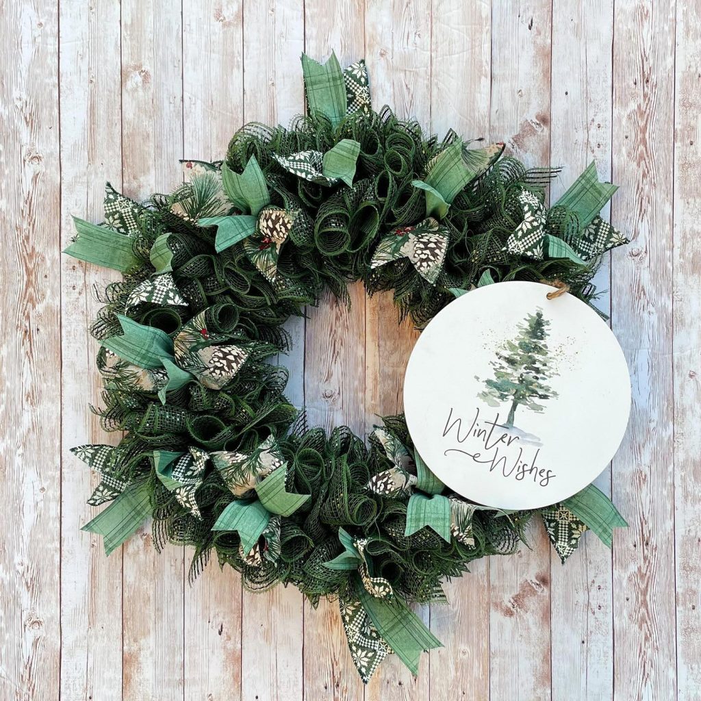 a green wreath with a tag saying 'winter wishes' on a background with vertical wood panels