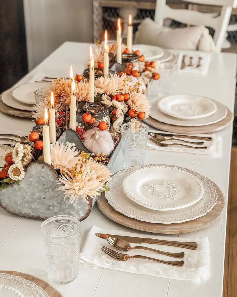 a cozy Thanksgiving tablescape with a centerpiece decorated with candles and white pumpkins