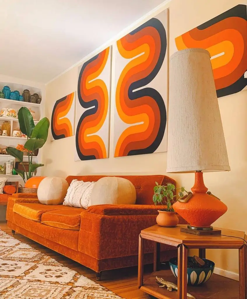 living space with bold orange and black wall art colors and an orange colored couch