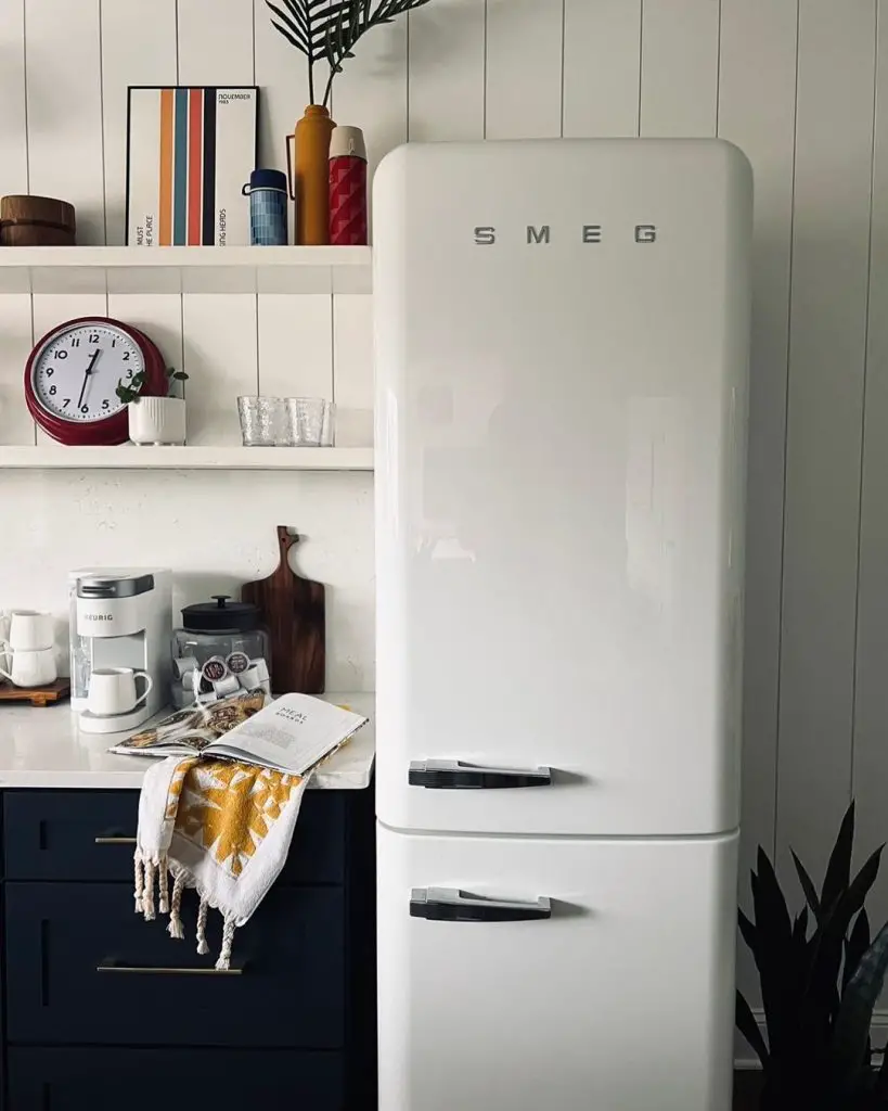 a white Smeg Fridge, kitchen cabinet and open wall shelves in a kitchen