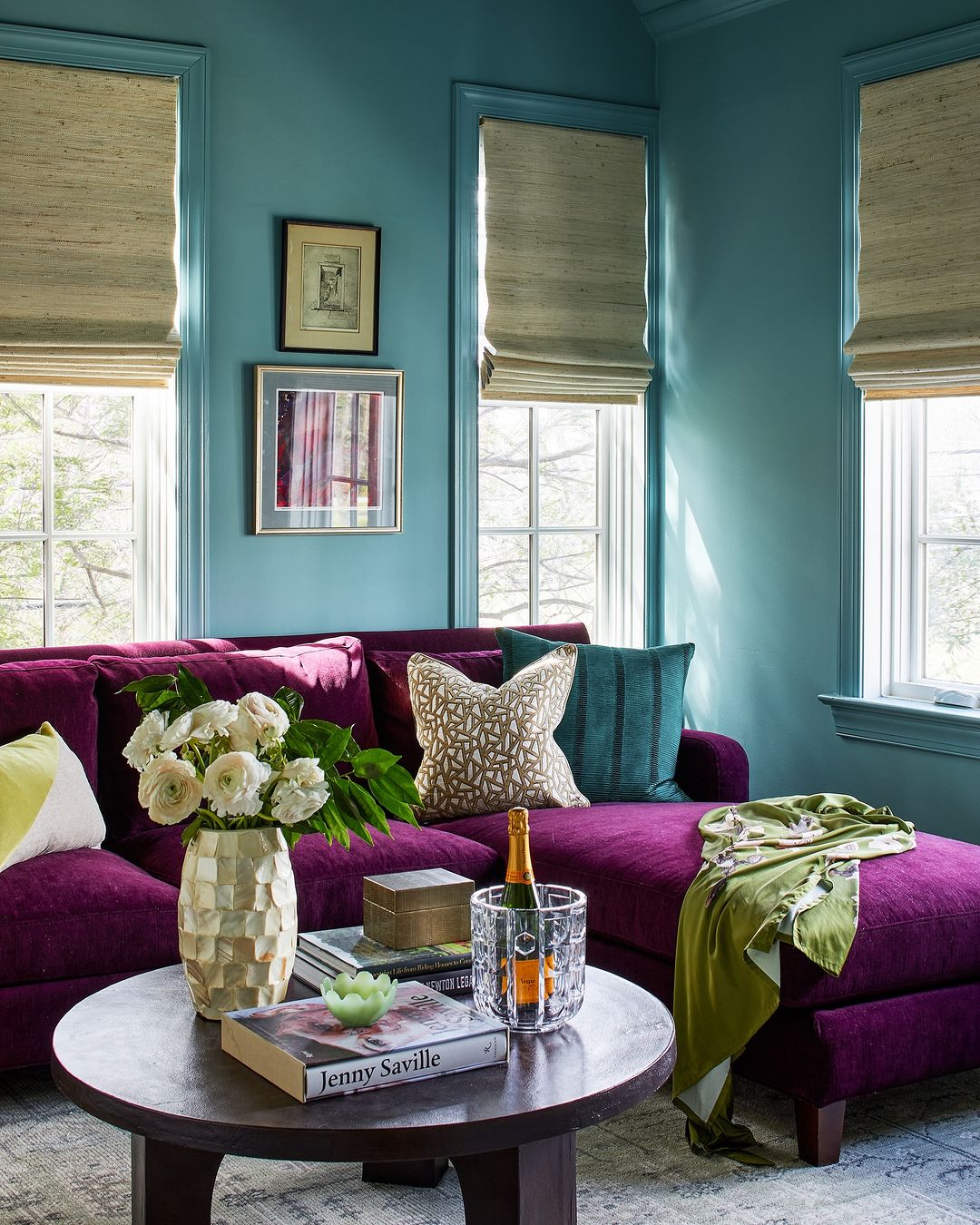 a velvet purple couch adds a pop of color to any living room as it does to this one