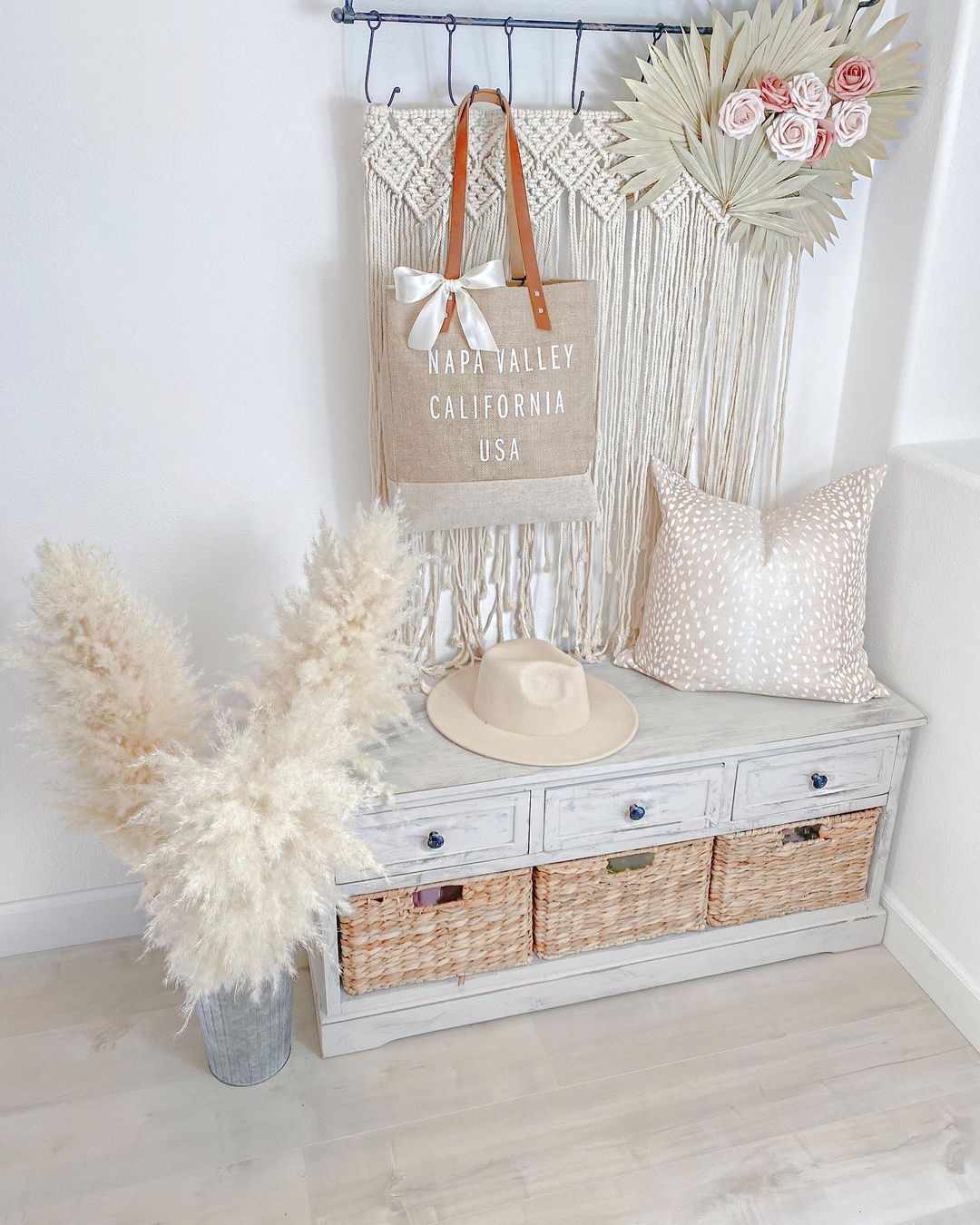 small entryway seating incorporating storage baskets and drawers with wall hangings, a hat, and a throw pillow to complete the decor