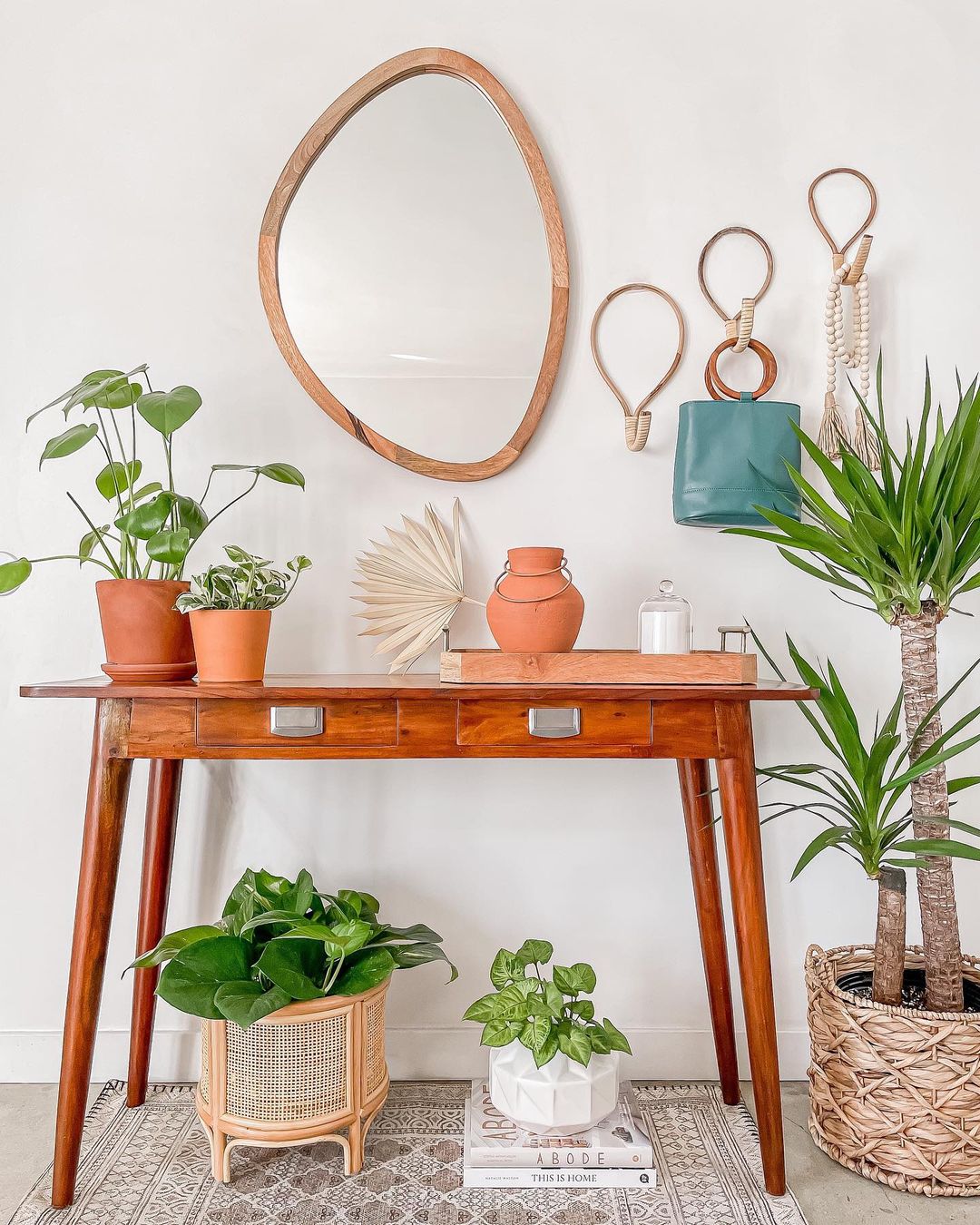entryway decor with a vibrant orange painted console table styled with potted green plants 