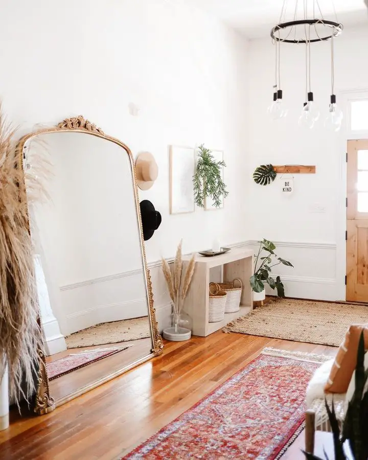 entryway decor with a large and tall wall leaning mirror, a console table, and some other decor accessories to complete the decor