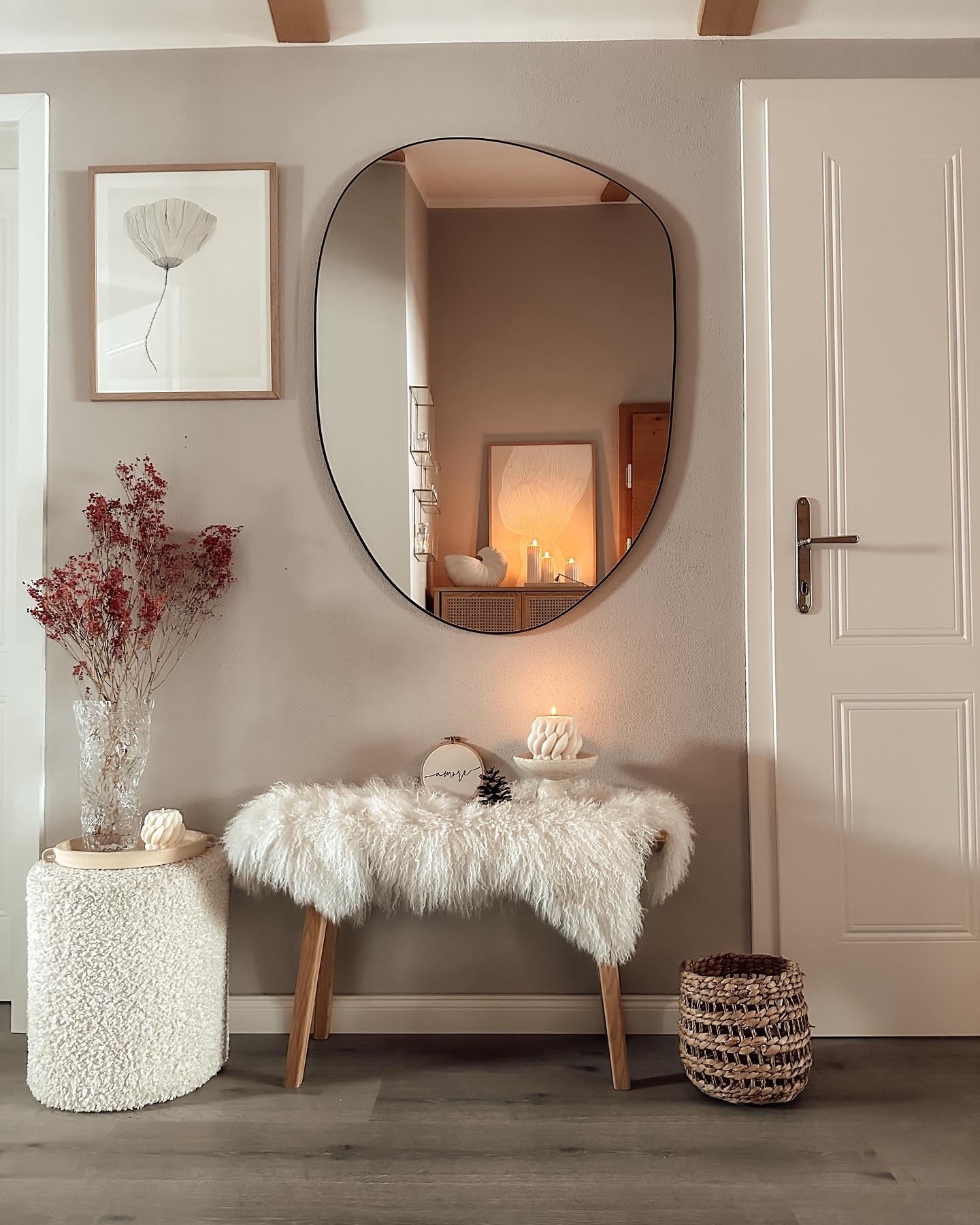 a console table styled with a plush blanket, a floor basket, and a wall mirror above make for the perfect accessories to decorate for a simple and neutral-toned winter entryway