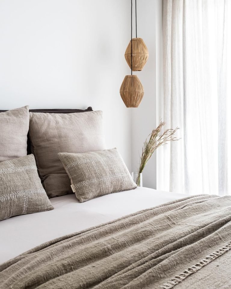 a bedroom with a bed, layered pillows, and a ceiling mounted modern bohemian inspired lights