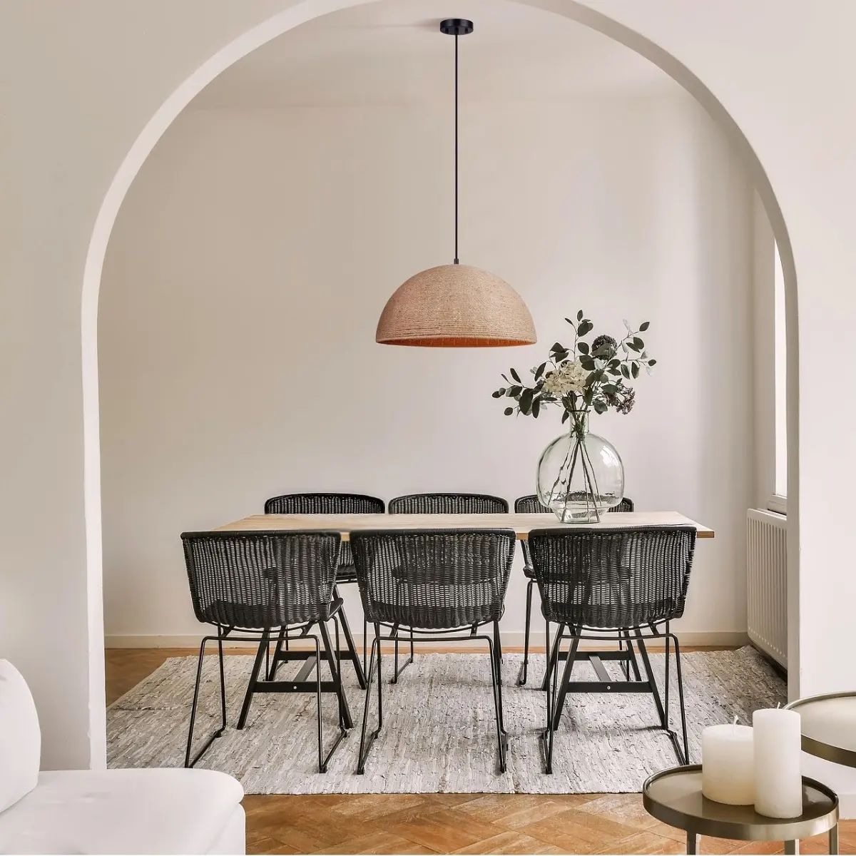 a dining room with minimal furniture and styled with a semi-circular pendant light reminiscent of bohemian style lighting to enhance the space