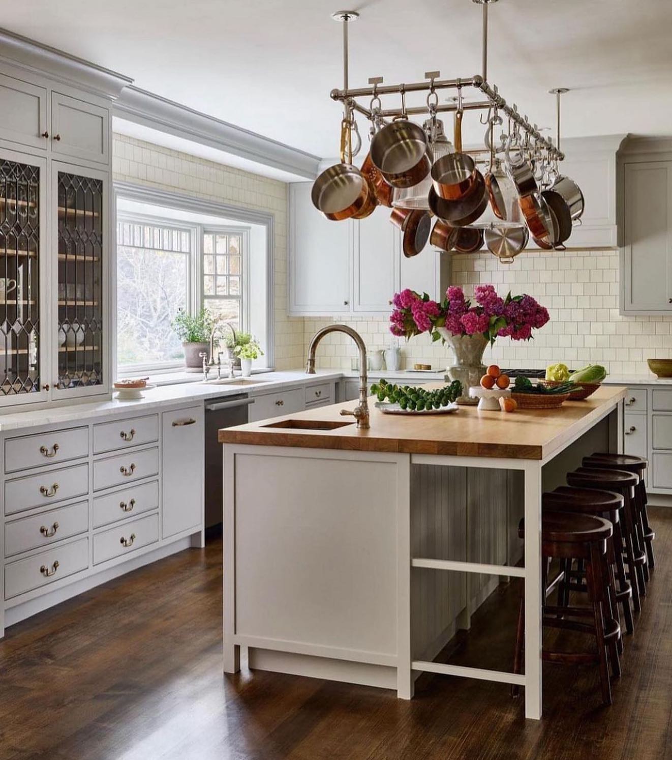 pots and pans rack suspended from the ceiling over a kitchen island adds a rustic element to this kitchen while being practical.