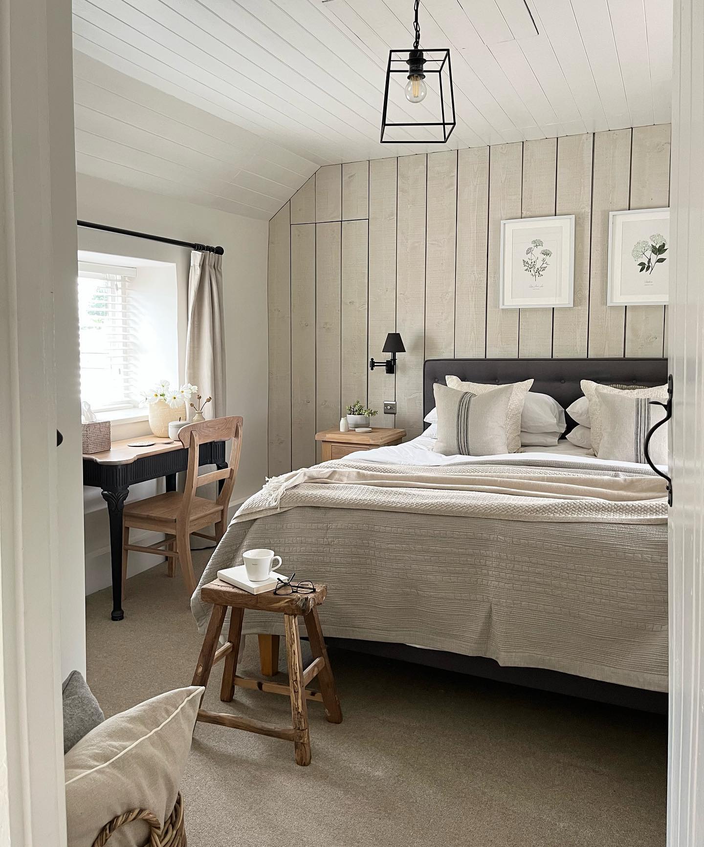 a modern cottage interior is palpable in this bedroom with wood paneling and furnishings along with linen bedding