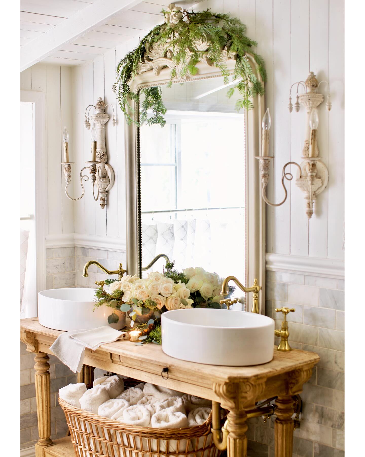 a double vanity with gold faucets in a bathroom with french style decor including wall sconces and a framed mirror is uplifting and ideal for a relaxed bathroom look