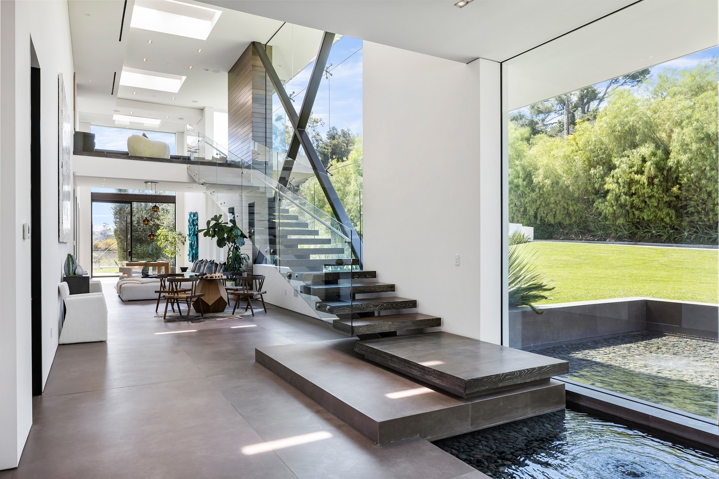 interior stair next to a water pond with large glass openings make this home interior both open and inviting