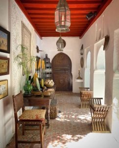 moroccan covered veranda with hanging lanterns and decorated with local furniture including chairs and a table