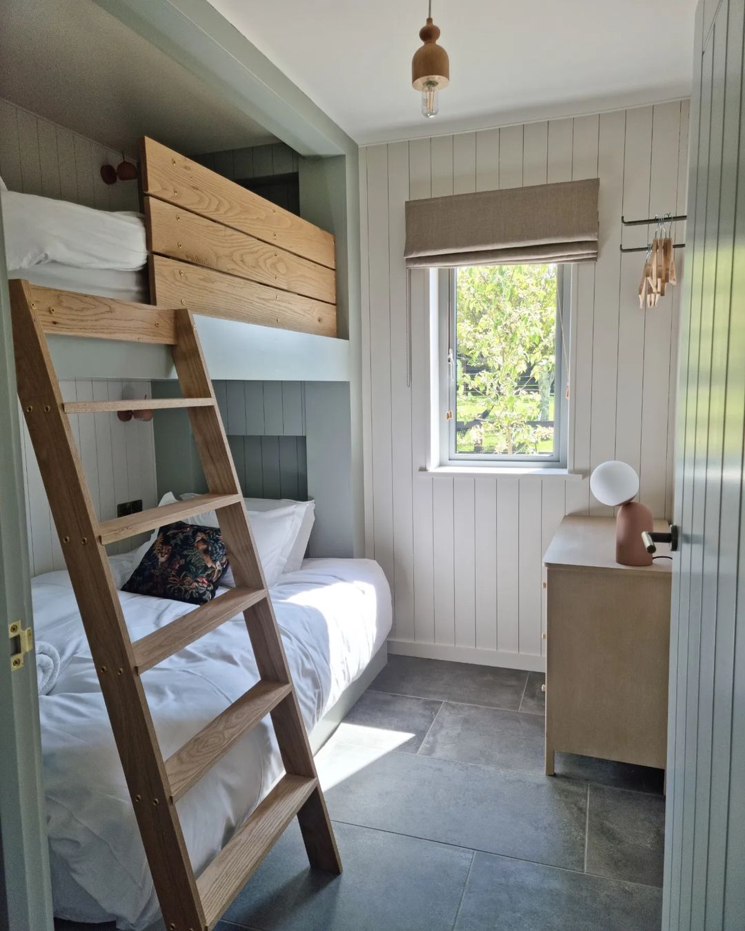 a small bedroom with a bunk bed with an attached ladder and a chest of drawers