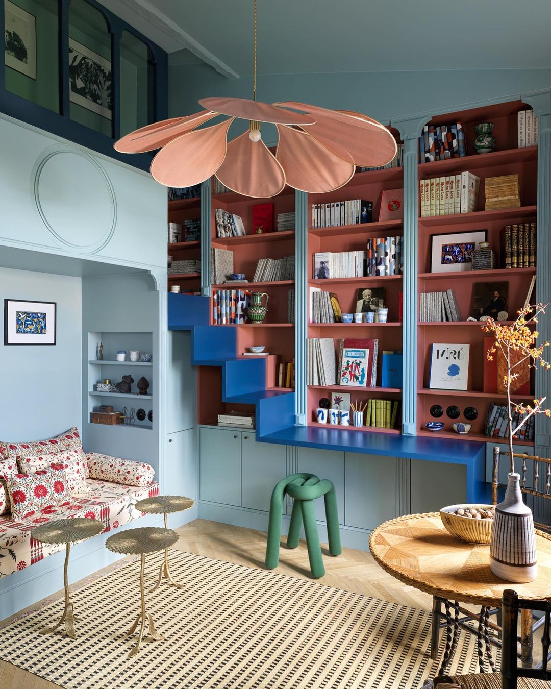 a colorful and small living area decorated with alcove seating and wall bookshelves a ceiling light and a small round table