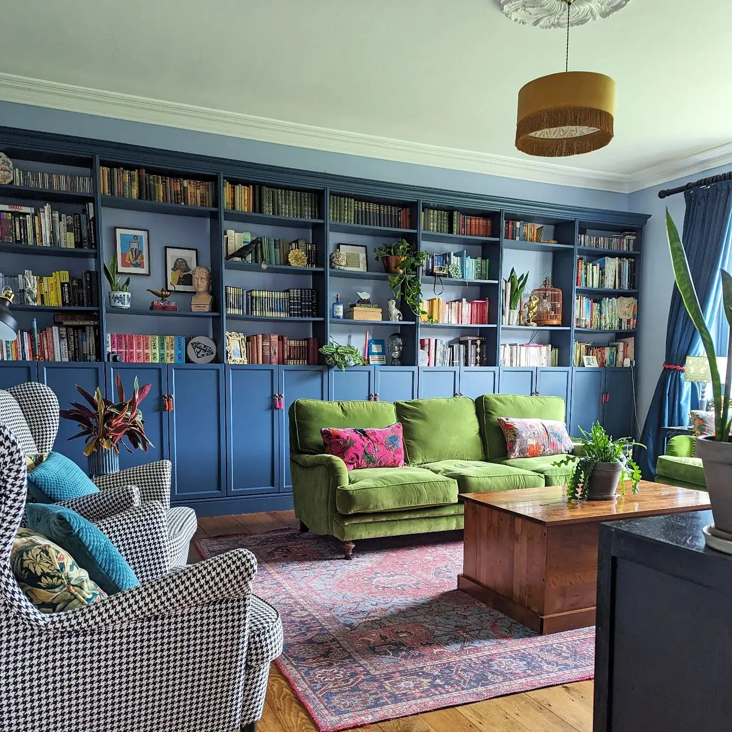 choosing the right color scheme for an eclectic living room can be daunting as well as fun as in this living room with a green couch and blue wall cabinet.