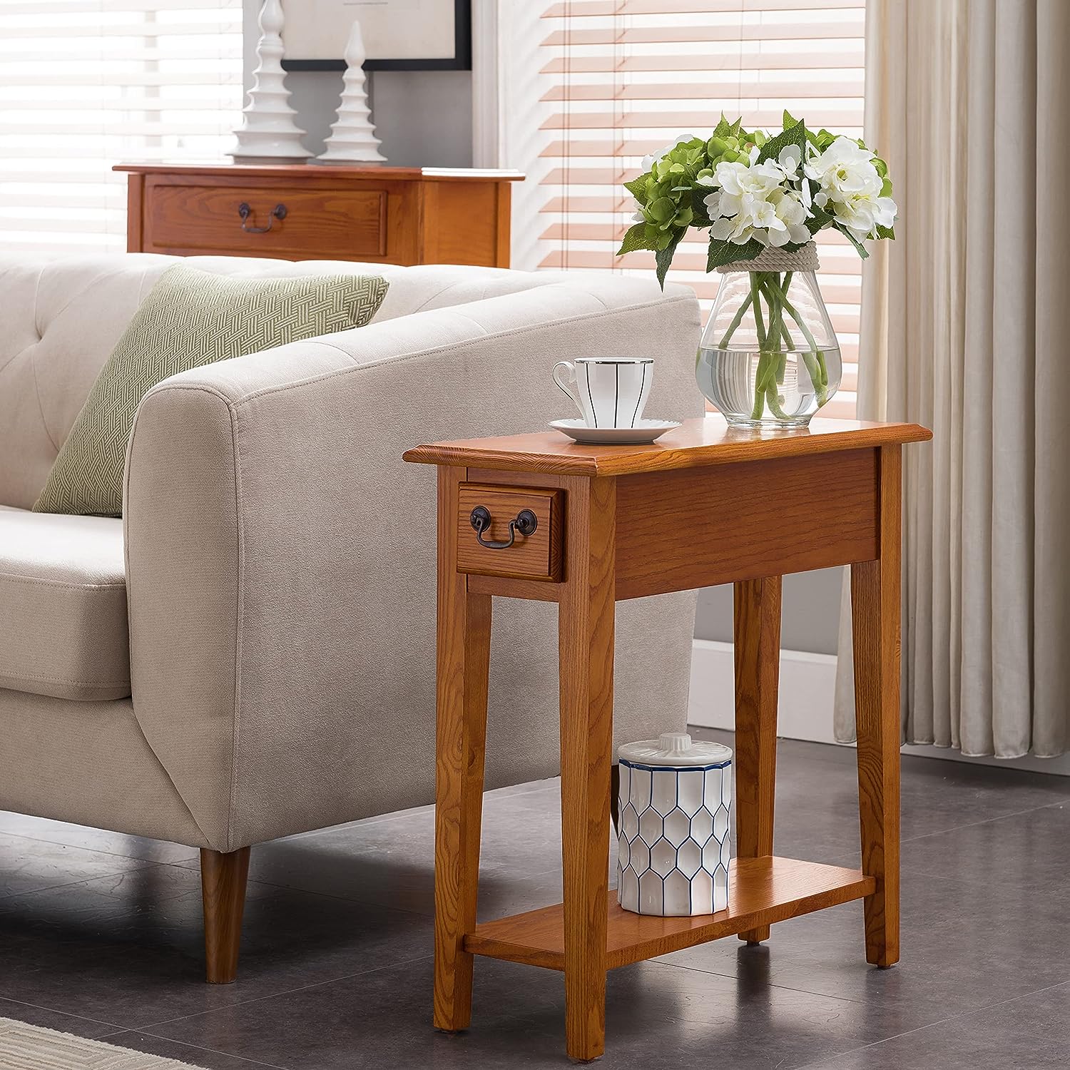 a classic slim end table next to a couch with an oak finish is perfect to add a farmhouse touch to this living space.
