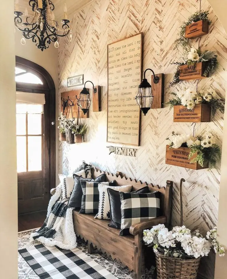 a farmhouse style wooden bench with pillow decor and wall sconces make this entryway warm and inviting.
