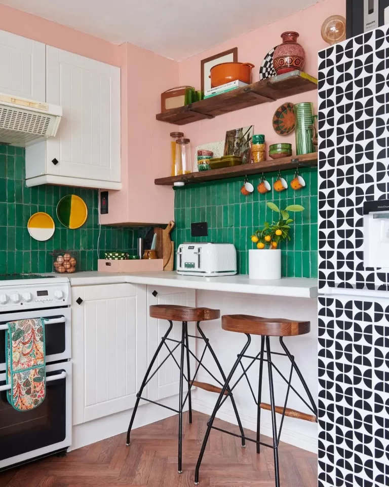 a funky looking kitchen with dark green backsplash and open shelving.