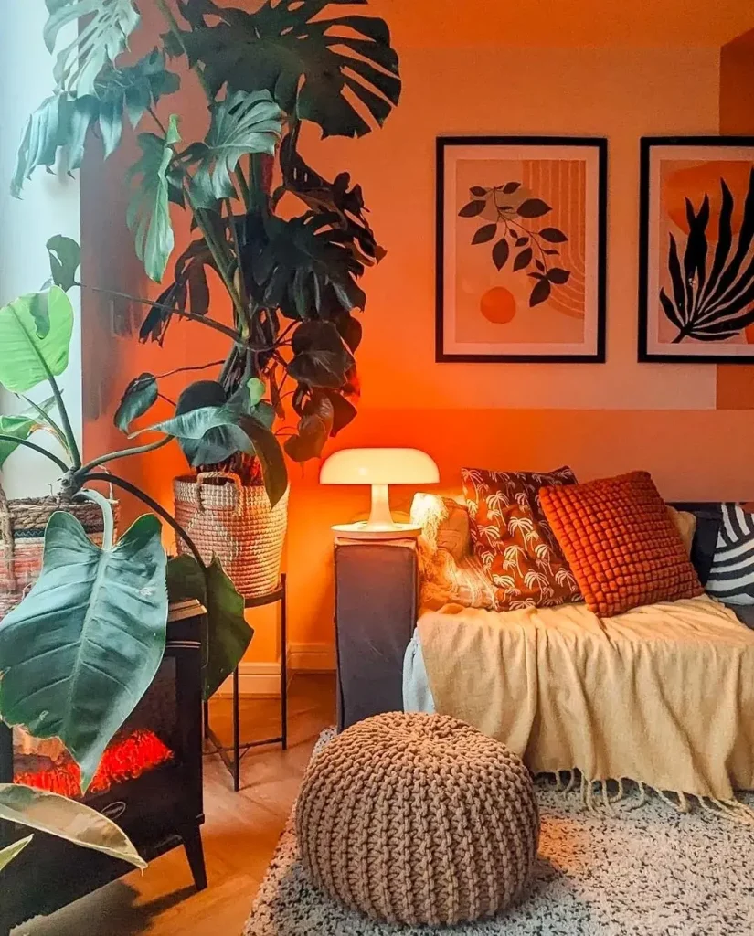 Cozy living room with a couch, blankets, a pouf, a glowing table lamp, potted plants, and framed botanical prints on the wall. Warm lighting creates a relaxed atmosphere—showcasing how to achieve funky Bohemian living room décor effortlessly.