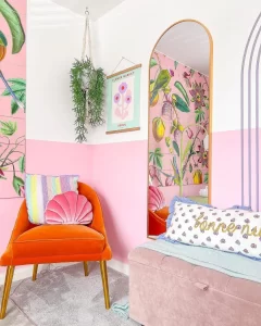 funky room decor showcasing a bold orange chair and pastel wall color and funky inspired wallpaper.