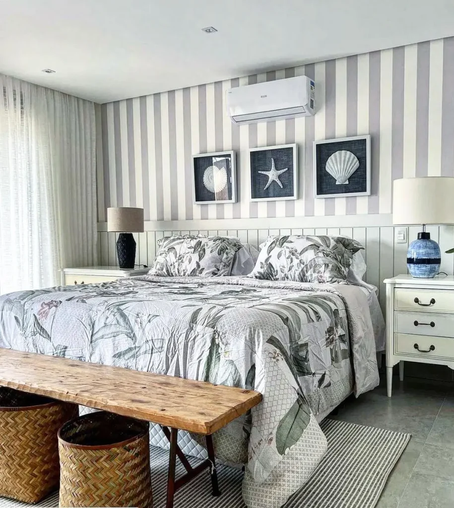 Beach-themed bedroom with floral bedding, striped wallpaper, and seashell artwork above the bed, showcasing affordable decorative accessories.