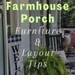 A farmhouse porch with a welcome sign, potted fern, black lantern light, white siding, and outdoor chairs—discover how to transform your farmhouse front porch for summer with our tips on furniture and layout.
